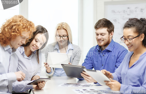 Image of smiling team with table pc and papers working