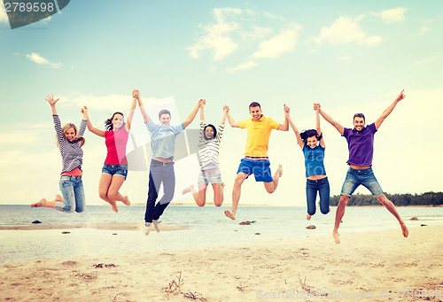 Image of group of friends jumping on the beach