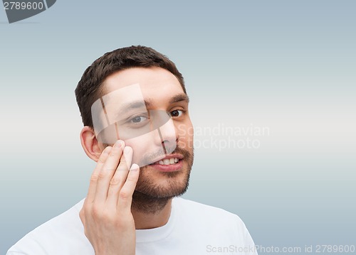 Image of beautiful smiling man touching his face