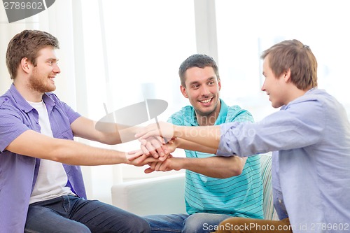 Image of smiling male friends with hands together at home