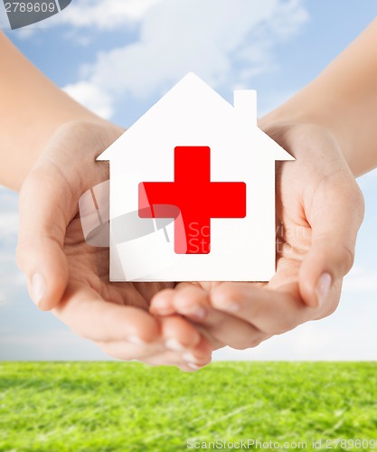 Image of hands holding paper house with red cross