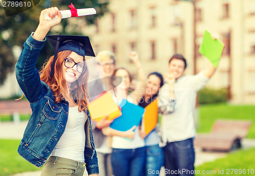 Image of smiling teenage girl in corner-cap with diploma