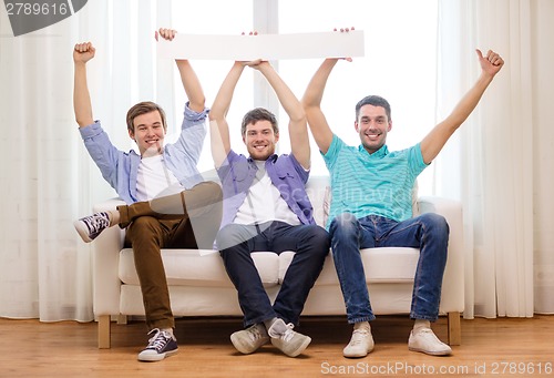 Image of smiling male friends holding white blank banner