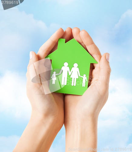 Image of hands holding green house with family