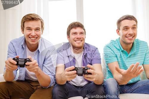Image of smiling friends playing video games at home