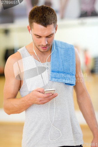 Image of young man with smartphone and towel in gym