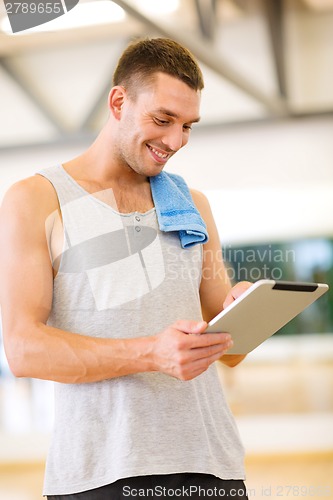 Image of young man with tablet pc computer and towel in gym