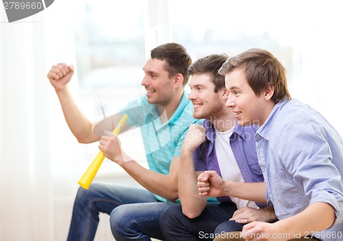 Image of happy male friends with vuvuzela watching sports