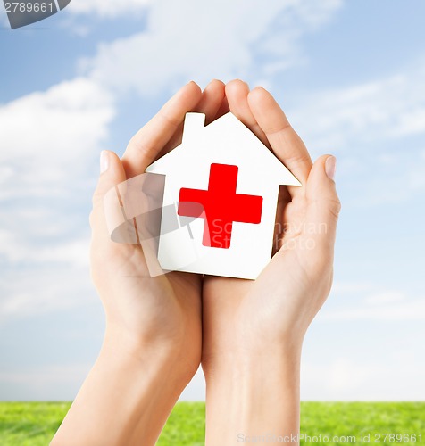 Image of hands holding paper house with red cross