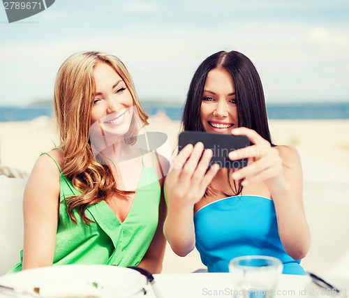 Image of girls taking photo in cafe on the beach