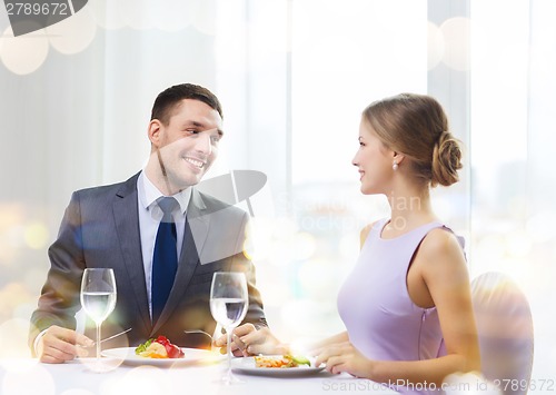 Image of smiling couple eating main course at restaurant