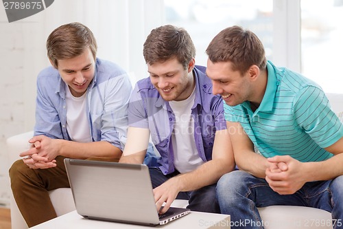Image of smiling friends with laptop computer at home