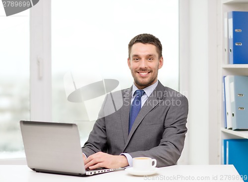 Image of smiling businessman with laptop and coffee