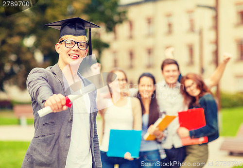 Image of smiling teenage boy in corner-cap with diploma