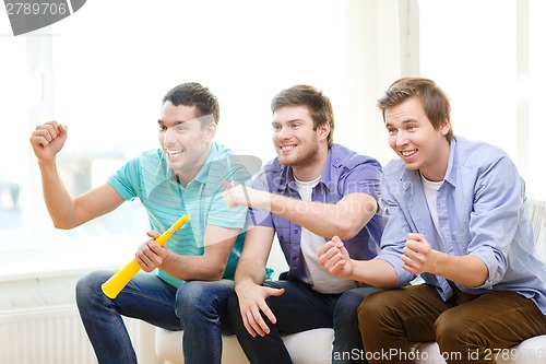 Image of happy male friends with vuvuzela watching sports