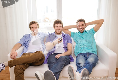 Image of smiling friends with remote control at home