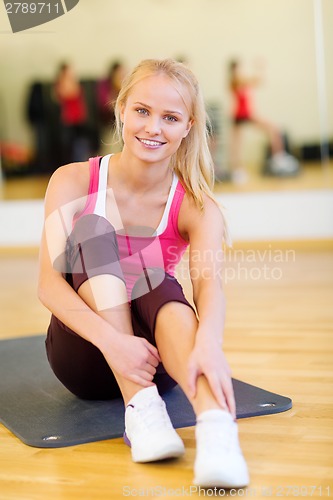 Image of smiling woman stretching on mat in the gym