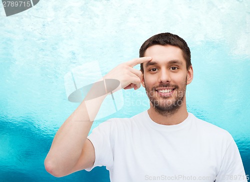 Image of smiling young handsome man pointing to forehead