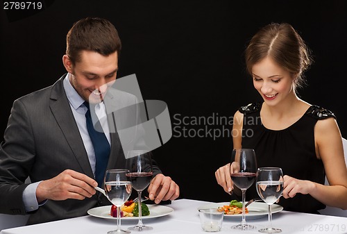 Image of smiling couple eating main course at restaurant