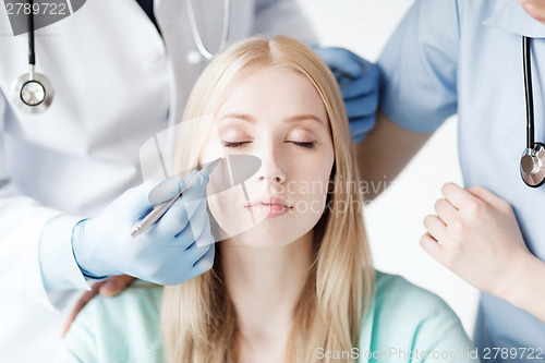 Image of plastic surgeon and nurse with patient