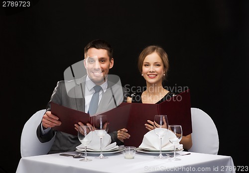 Image of smiling couple with menus at restaurant