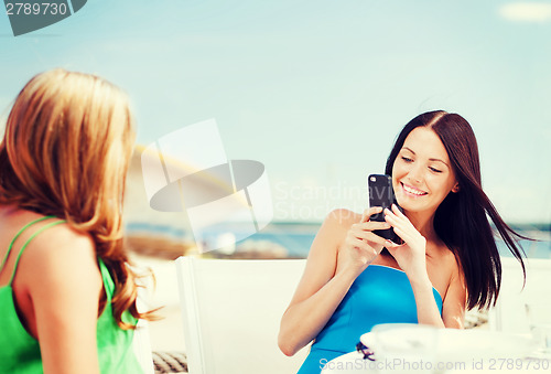 Image of girls taking photo in cafe on the beach