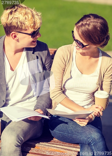 Image of two students with books, notebooks and folders