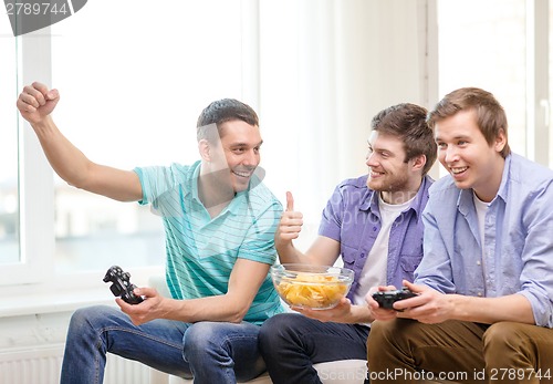 Image of smiling friends playing video games at home