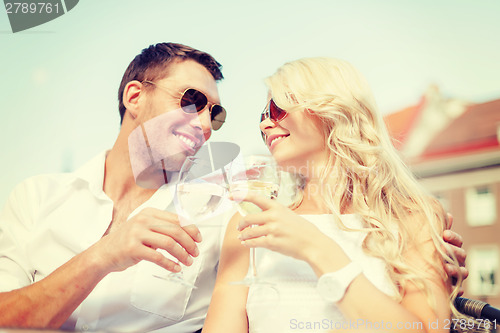 Image of smiling couple in sunglasses drinking wine in cafe