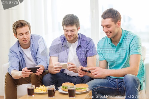 Image of smiling friends taking picture of food at home