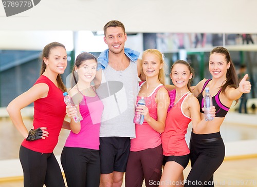 Image of group of happy people in gym with water bottles