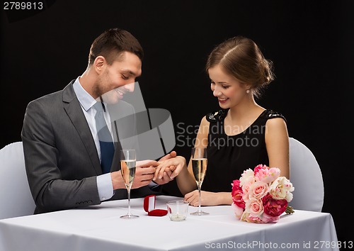 Image of man proposing to his girlfriend at restaurant