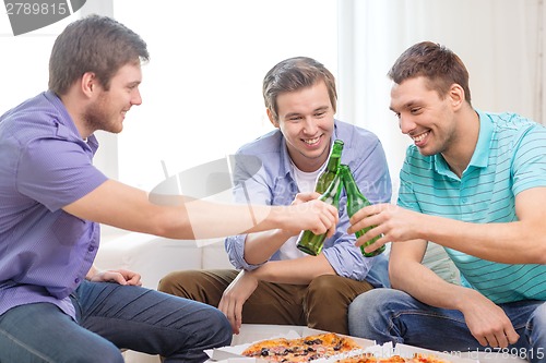 Image of smiling friends with beer and pizza hanging out