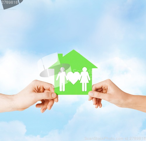 Image of hands holding green house with family