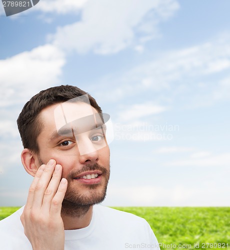 Image of beautiful smiling man touching his face