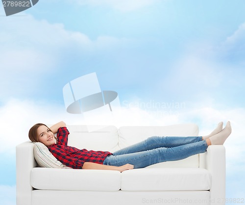 Image of smiling teenage girl lying on sofa