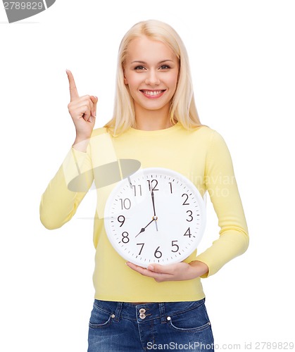 Image of student with wall clock and finger up