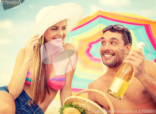 Image of smiling couple having picnic on the beach