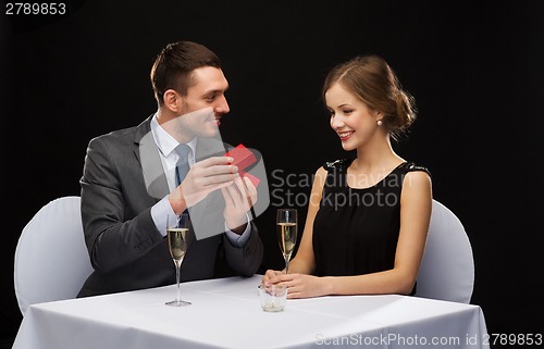 Image of excited young woman looking at boyfriend with box
