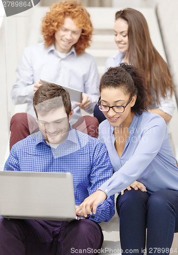 Image of team with laptop and tablet pc on staircase