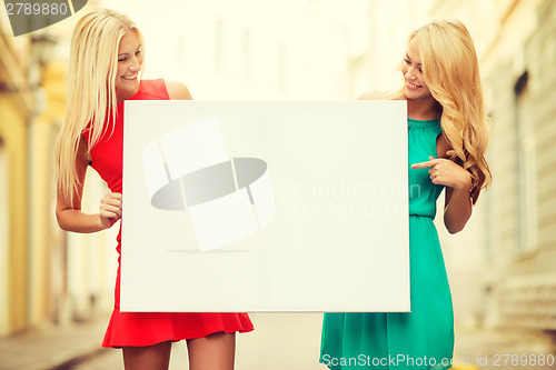 Image of two happy blonde women with blank white board