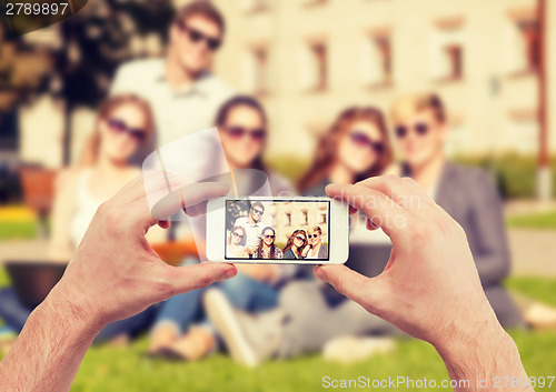 Image of close up of hands making picture of group of teens