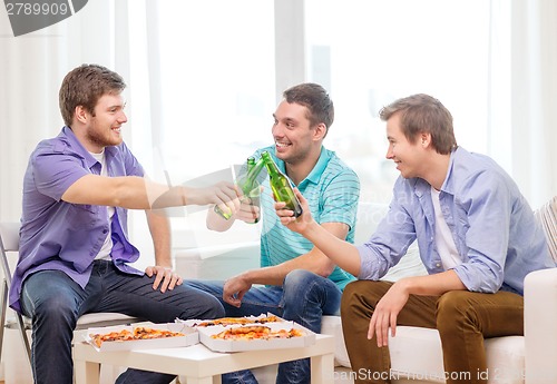 Image of smiling friends with beer and pizza hanging out