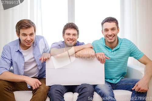 Image of smiling male friends holding white blank board