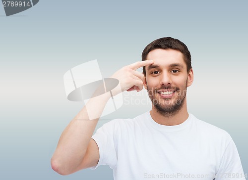 Image of smiling young handsome man pointing to forehead