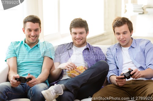 Image of smiling friends playing video games at home