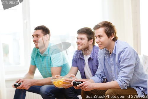 Image of smiling friends playing video games at home