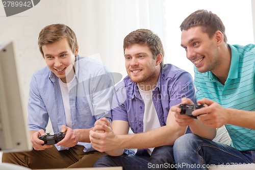 Image of smiling friends playing video games at home