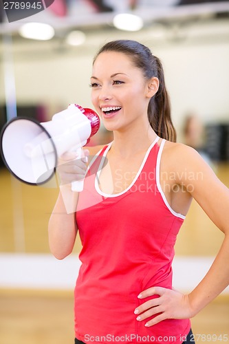 Image of beautiful sporty woman with megaphone at gym