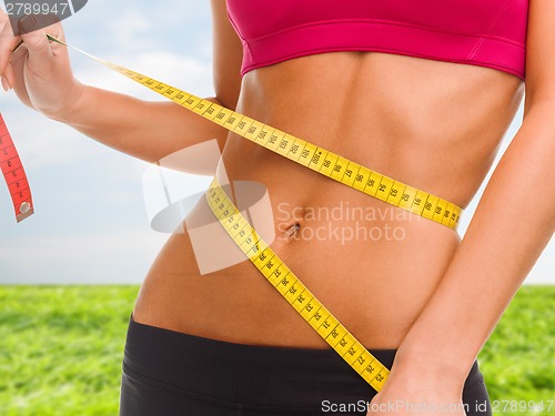 Image of close up of trained belly with measuring tape